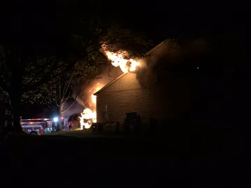 Flames and smoke pouring from a two-story house at night