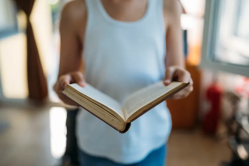 A person holding an open book with both hands