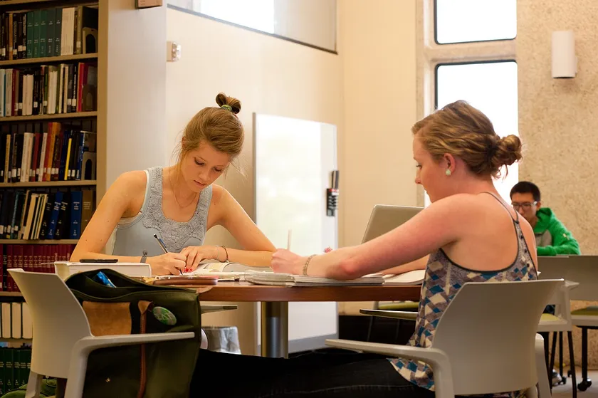 Young adults studying together at tables in a busy library