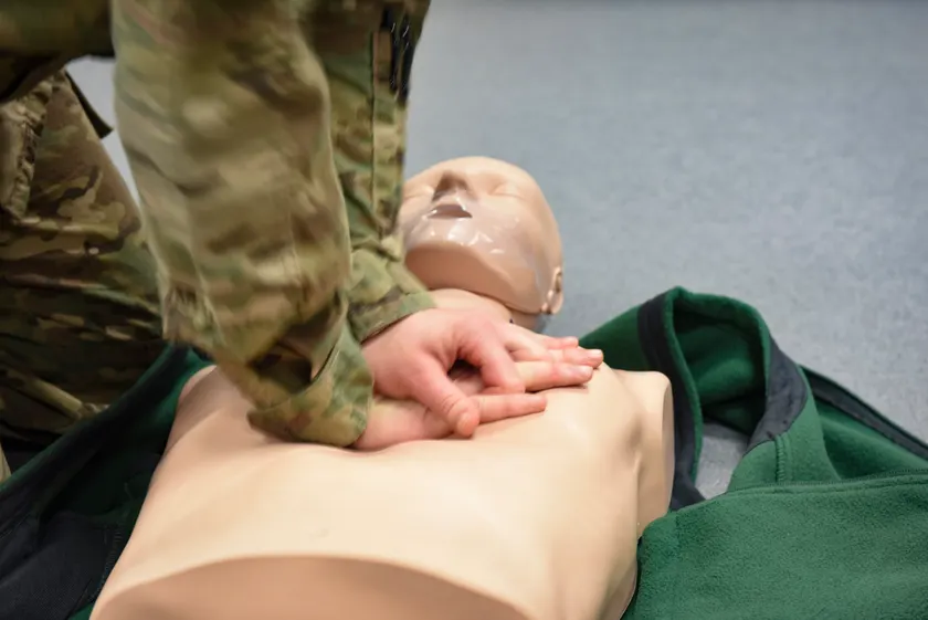 A person practicing chest compressions on a CPR training mannequin
