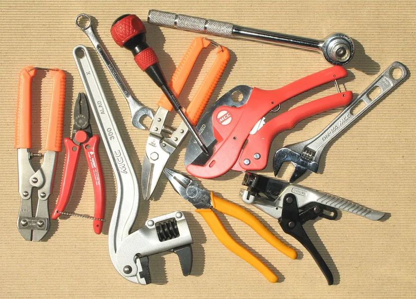 A row of hand tools, including pliers, wrenches, screwdrivers, and cutters