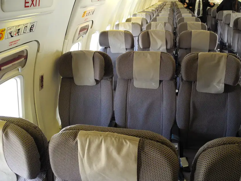 Rows of empty blue airplane seats in a passenger cabin
