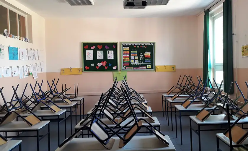 An empty classroom with desks, a blackboard, and no people