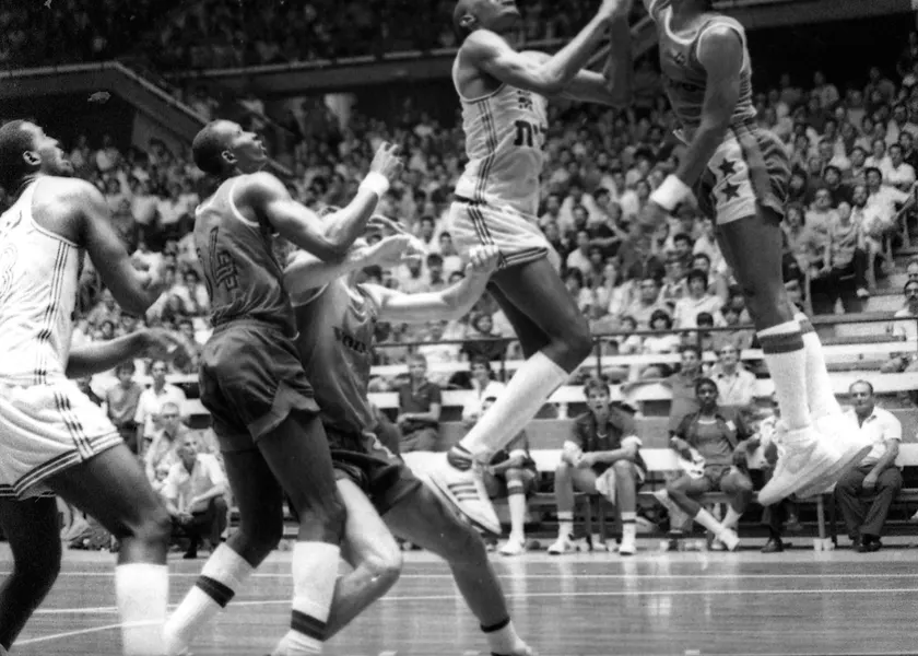Adult basketball players leaping toward the basket