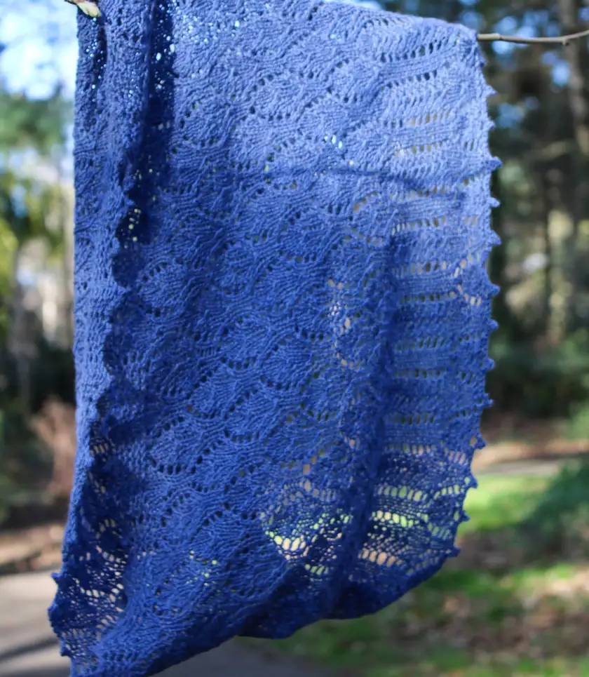 A blue knitted wrap hanging outdoors