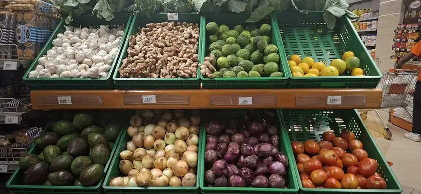 A pile of tomatoes, onions, avocados, lemons, garlic, and ginger