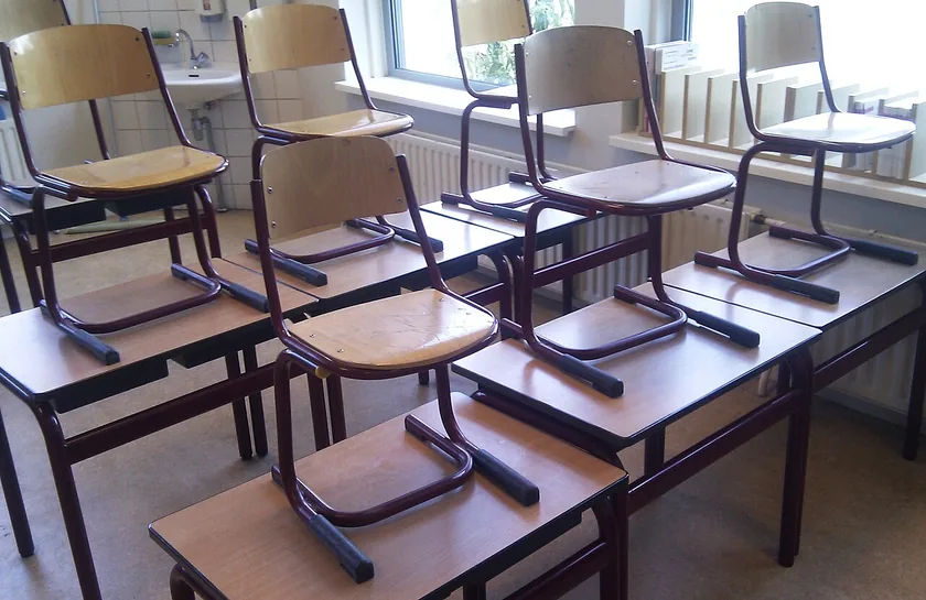 An empty classroom with rows of wooden desks and a chalkboard