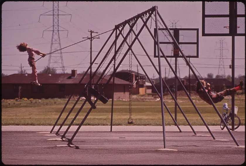 Two children on a swing set, seen from behind