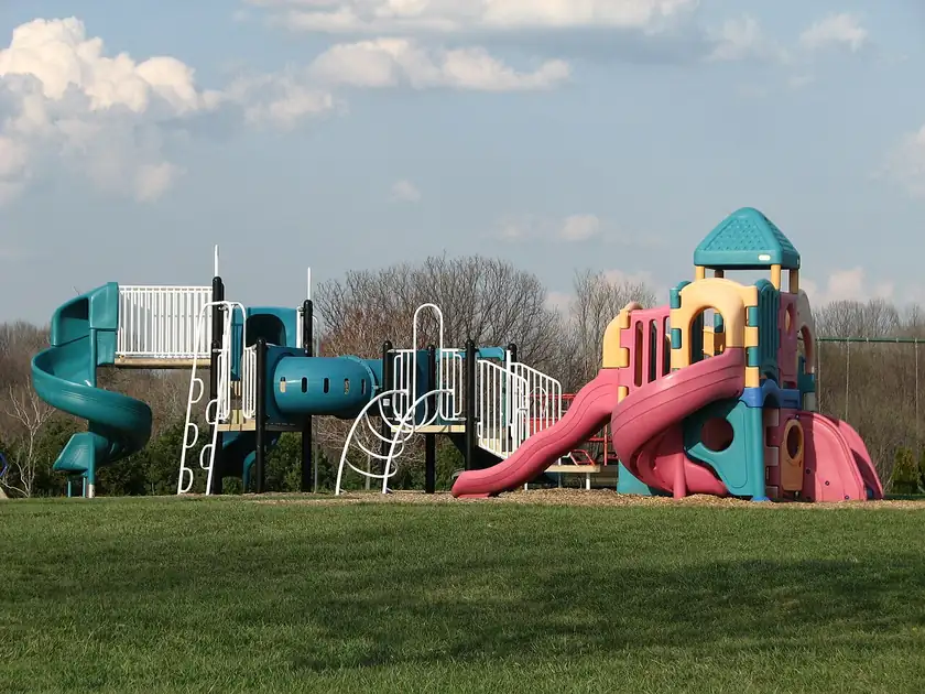 An empty playground with slides and climbing structures and no children in the frame