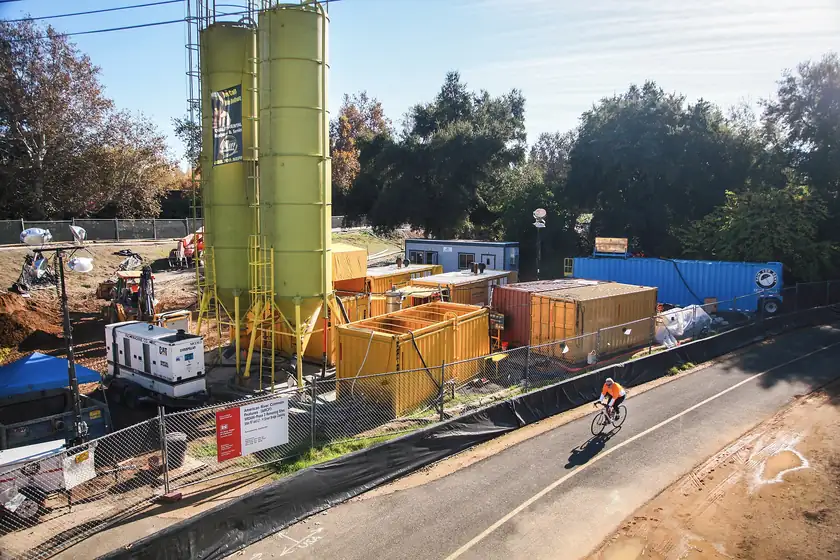 A paved trail beside a levee construction zone, with a white truck and no people close to the camera