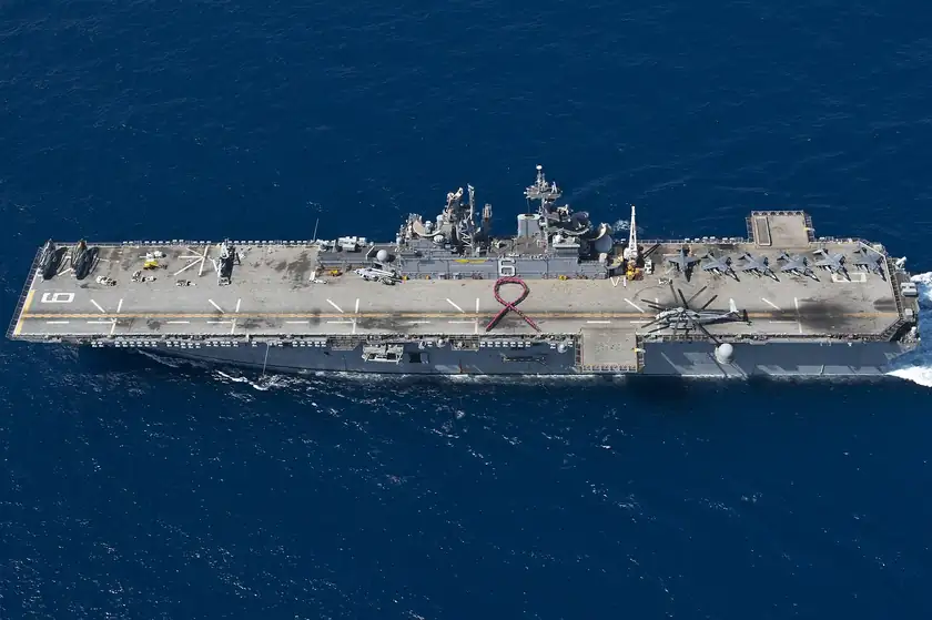 Sailors in pink shirts standing in the shape of a ribbon on a ship's deck