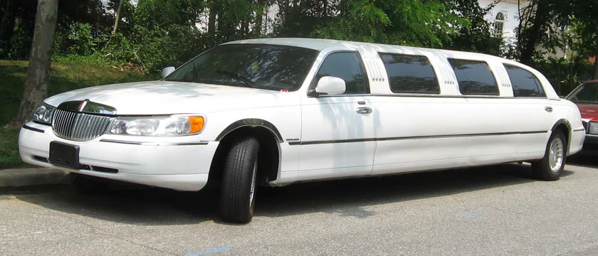 A white stretch limousine parked on pavement, seen from the side