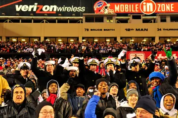A crowd of spectators cheering in the stands at a football stadium