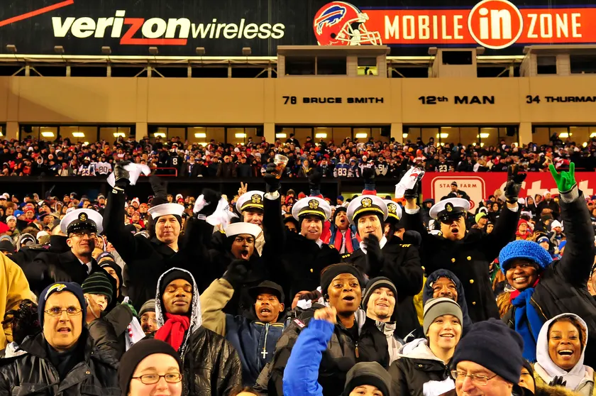 A crowd of spectators cheering in the stands at a football stadium