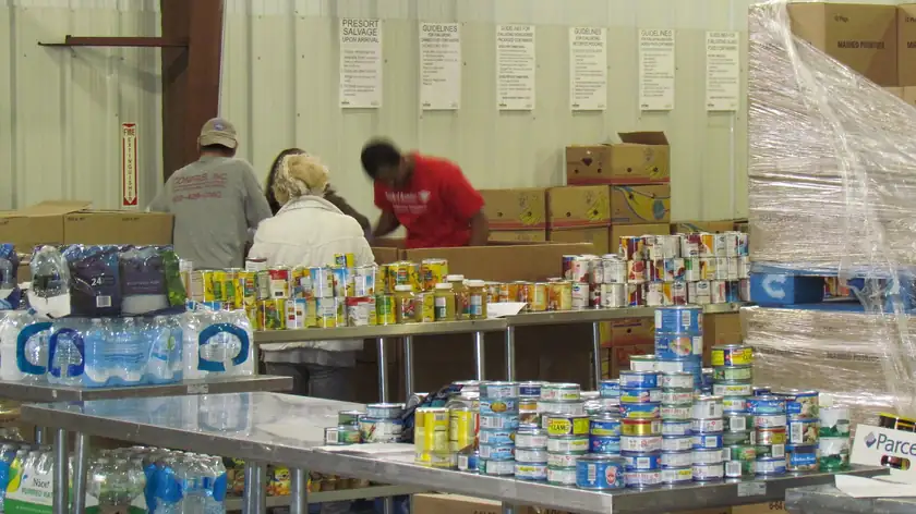 Volunteers in gloves sorting donated goods on long tables
