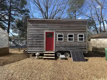 A small wooden tiny house with a porch, and no people