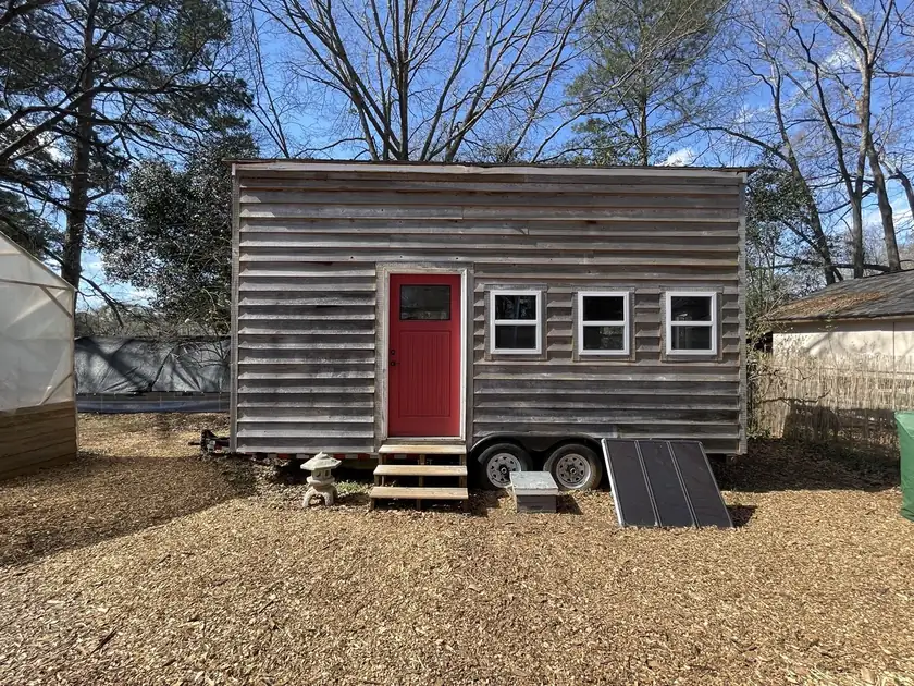 A small wooden tiny house with a porch, and no people