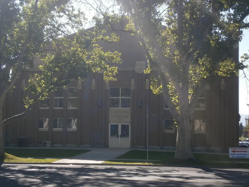 An empty high school gym with a basketball court and folded bleachers