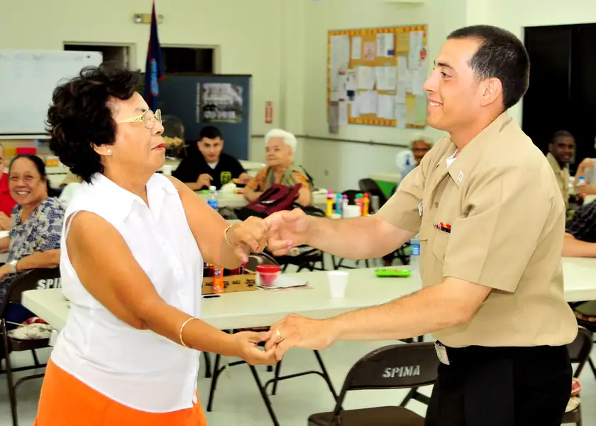 An older woman dancing with a sailor at a senior center