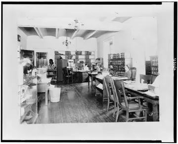 People working at desks in a reading room lined with books
