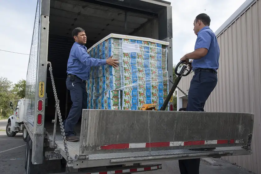 Two men unloading a pallet of canned food from a box truck