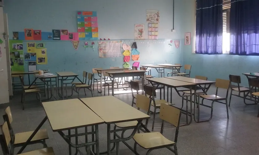 An empty classroom with rows of desks facing a whiteboard