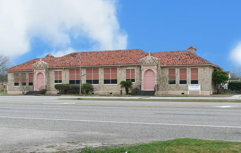 A brick high school building with a covered entrance and a parking lot