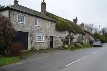 A row of small brick cottages with dark roofs and no people in front
