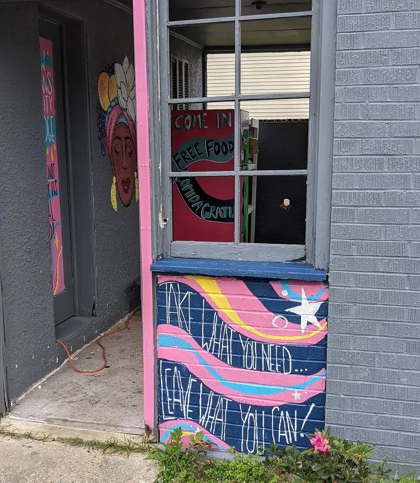 The entrance of a small community fridge painted with the words free food