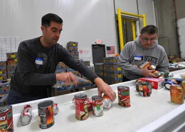 Two volunteers sorting canned food at a food-bank table