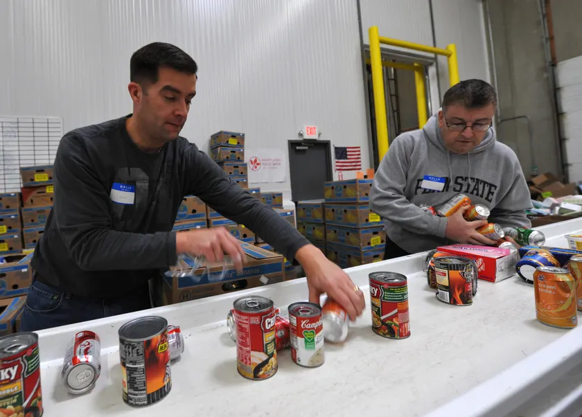 Two volunteers sorting canned food at a food-bank table