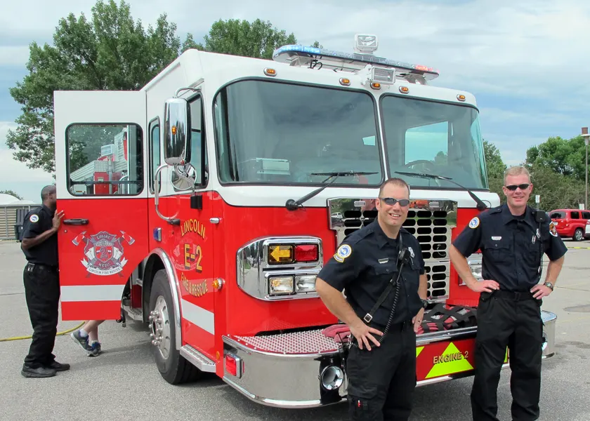 Firefighters standing with a fire engine outside the station