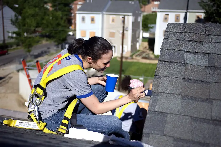 Volunteers in work clothes painting the side of a house