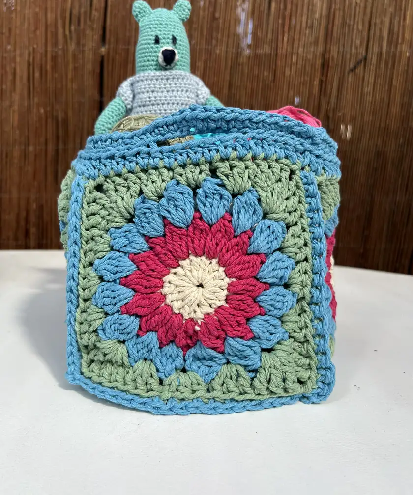 A basket filled with colorful crocheted granny squares, with no people