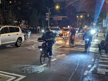 Adults in Halloween costumes riding bicycles on a city street