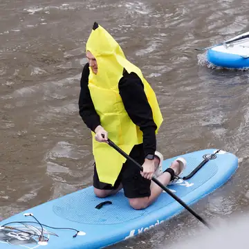 A person in a full banana costume standing on a boat deck