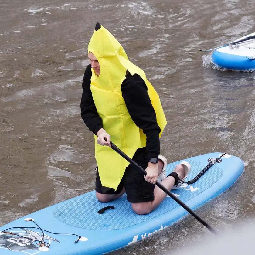 A person in a full banana costume standing on a boat deck