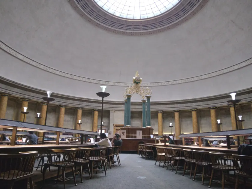 People reading at long tables in a grand library room