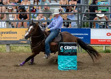 A rider on a galloping horse turning a barrel in an arena