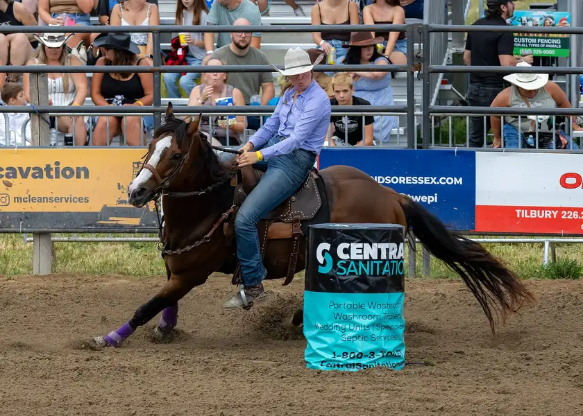 A rider on a galloping horse turning a barrel in an arena