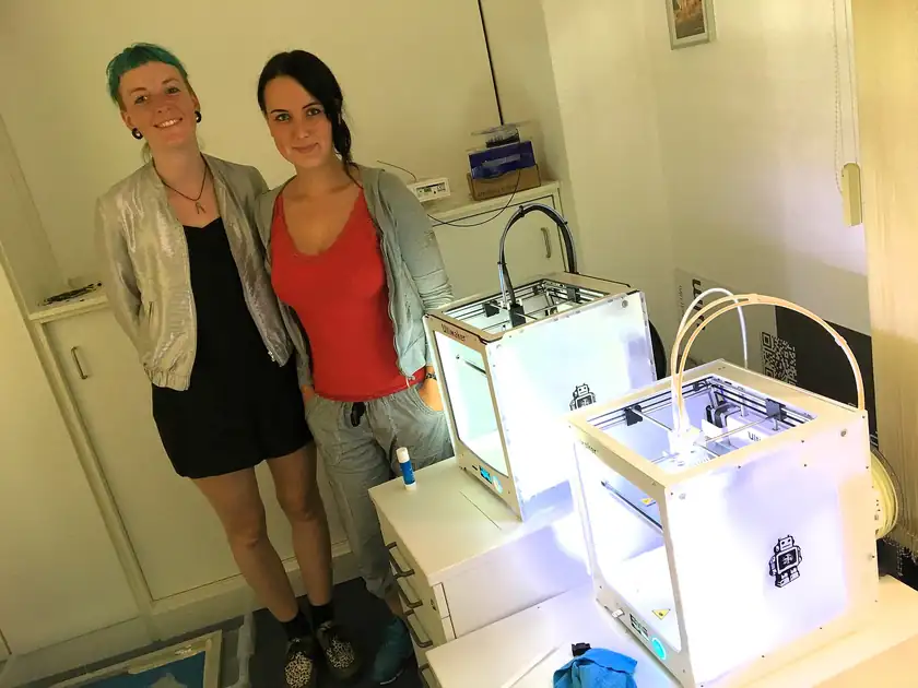 Adult hands adjusting a small object on a 3D printer