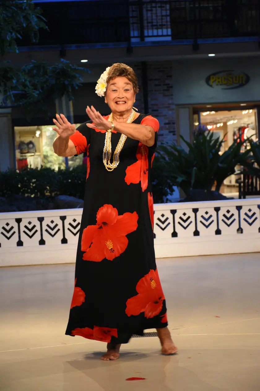 An older woman dancing with both arms raised