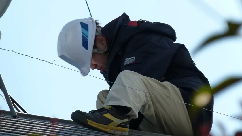A technician installing solar panels on a rooftop