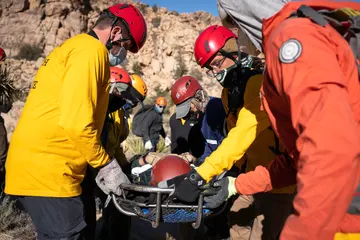 Search-and-rescue team members carrying a litter along a desert trail