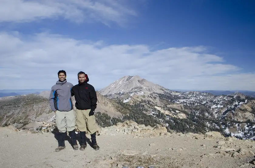 Two hikers seen from behind on a rocky mountain summit