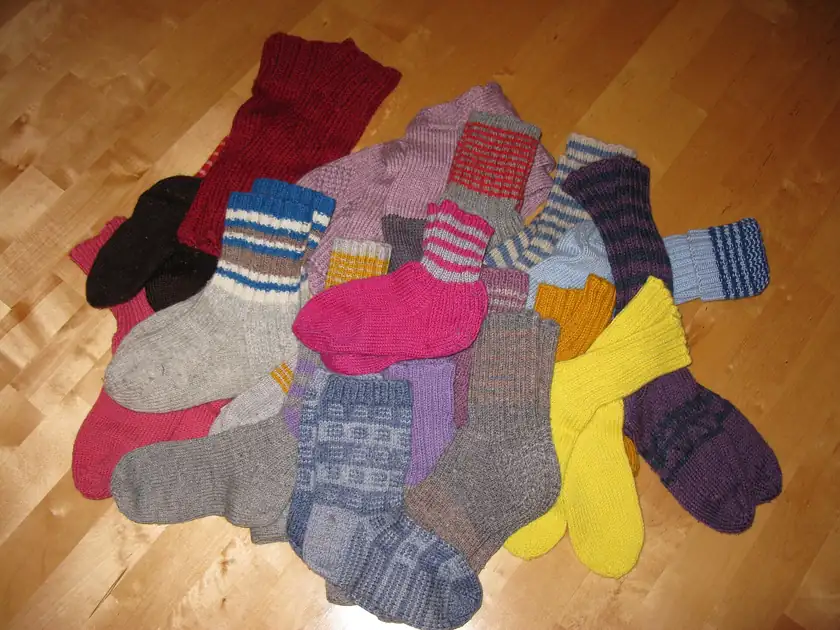 Several pairs of thick wool socks laid out on a wooden floor