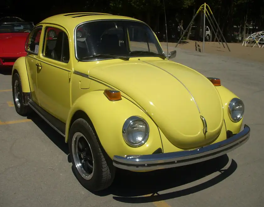 A 1973 Volkswagen Beetle hatchback parked on pavement with no people nearby