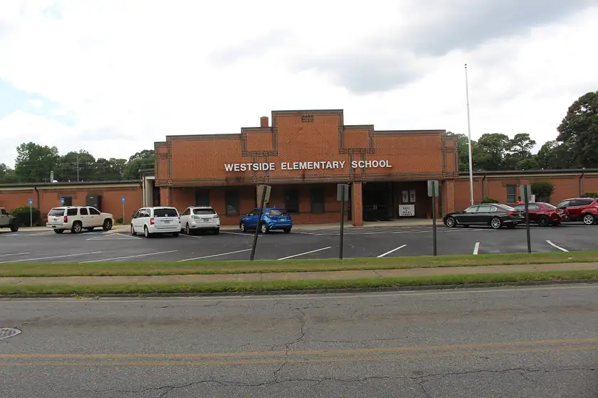A one-story brick elementary school with a covered walkway and no students outside