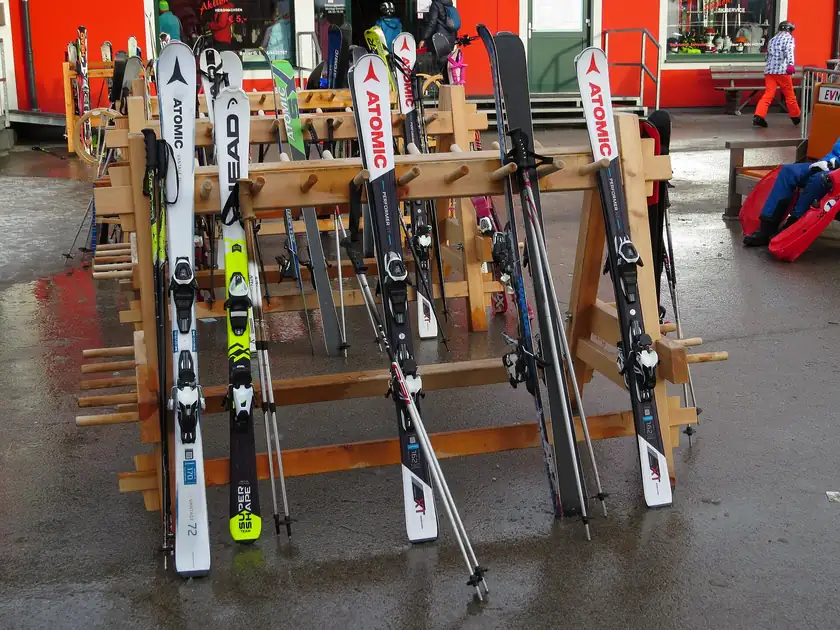 Rows of alpine skis standing in a wooden rack outside a shop