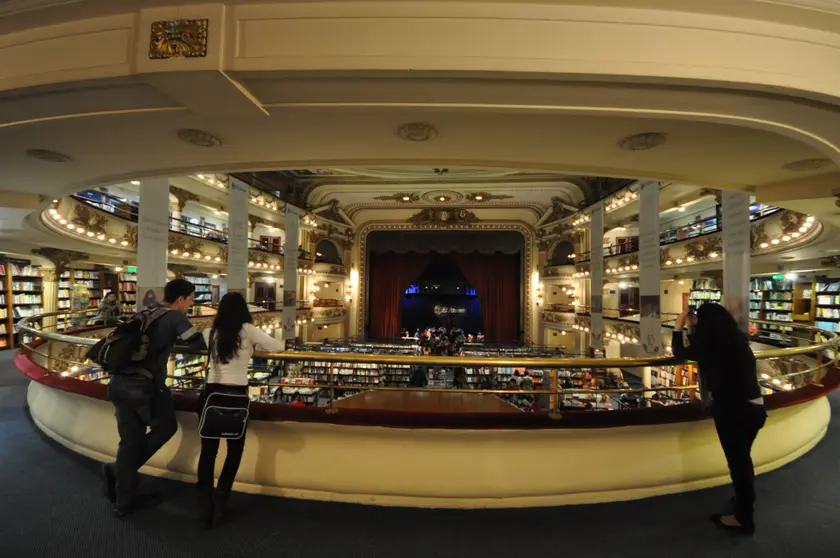 Adults browsing tall wooden bookshelves in a grand bookshop